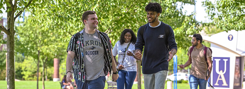 Four students talk while walking to class outdoors