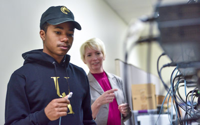 A student works with a professor in a computer networking lab