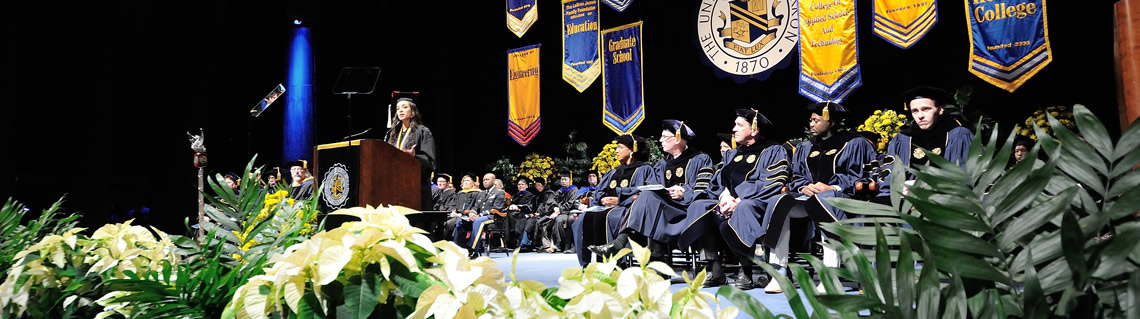 A speaker at commencement addresses an auditorium full of graduates and parents