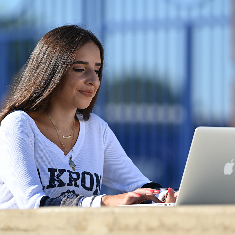 Three students share a laugh while seated outdoors on the UA campus