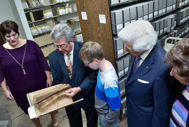 Many people examining a book in an archival storage area