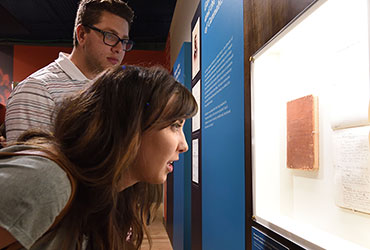 Two people leaning in to examine a museum display