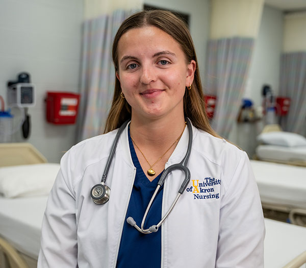 A portrait of a nursing student with a white lab coat and a stethoscope around their neck.