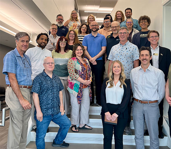 Group of 20 men and women who make up the academic and leadership team of Buchtel College of Arts and Sciences standing on stairs and smiling to camera.