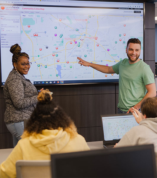 Students examine and discuss data displayed on a large interactive map in a classroom.