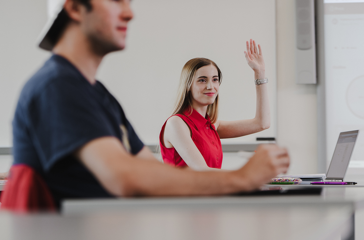 A student raising her hand in a classroom