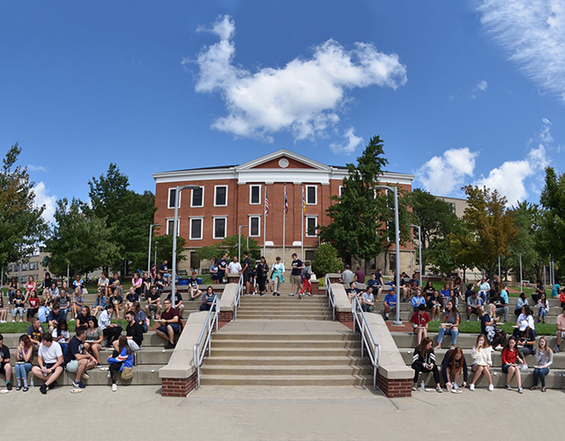 A wide shot of Buchtel Commons in the center of campus on a beautiful day with a lot of UA students around.
