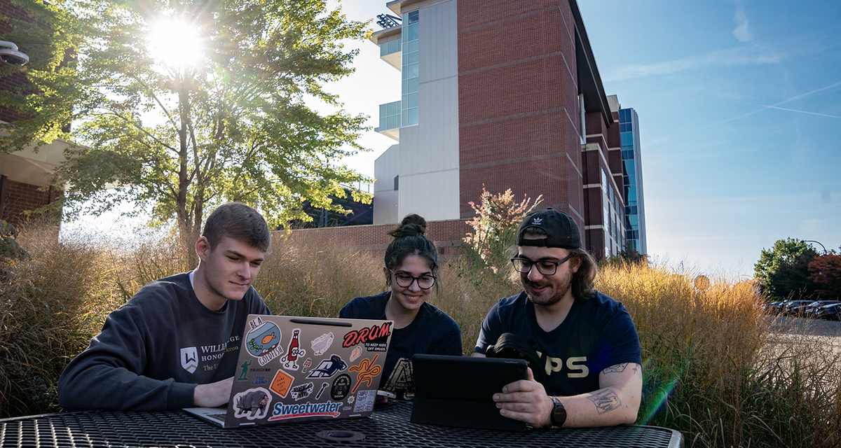 UA students seated outside with laptops