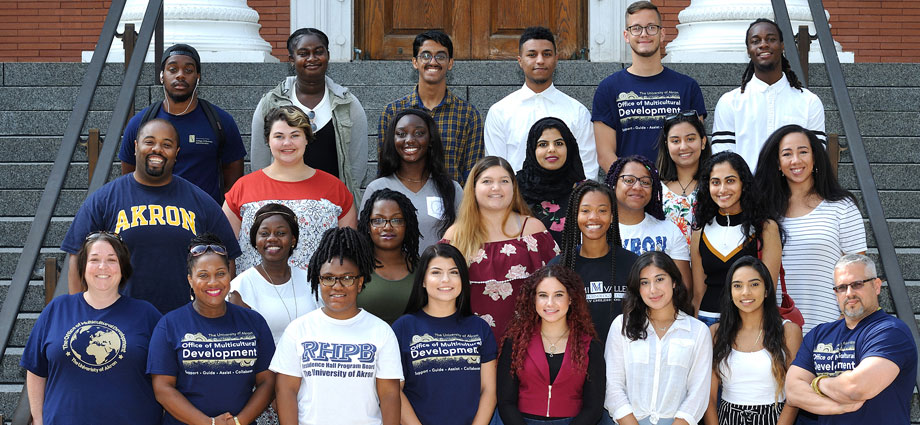 A group of peer mentors stand for a group photo on the steps of a campus building