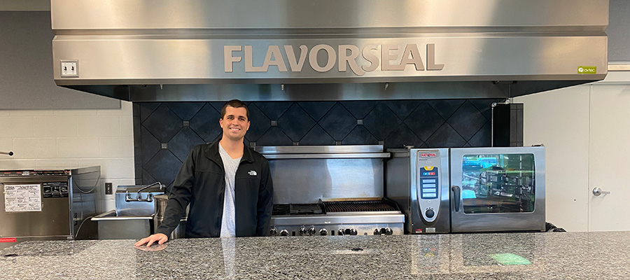 Man wearing black jacket and gray shirt in front of Flavorseal logo