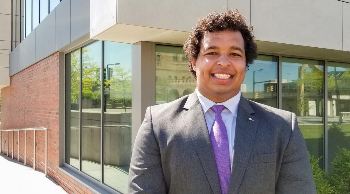 Maxwell Nixon is the inaugural recipient of the Charles Schwab Foundation Endowed Scholarship for Financial Planning at
            The University of Akron, stands on campus on a sunny day