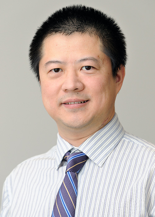 Headshot of man with dark hair against light background.