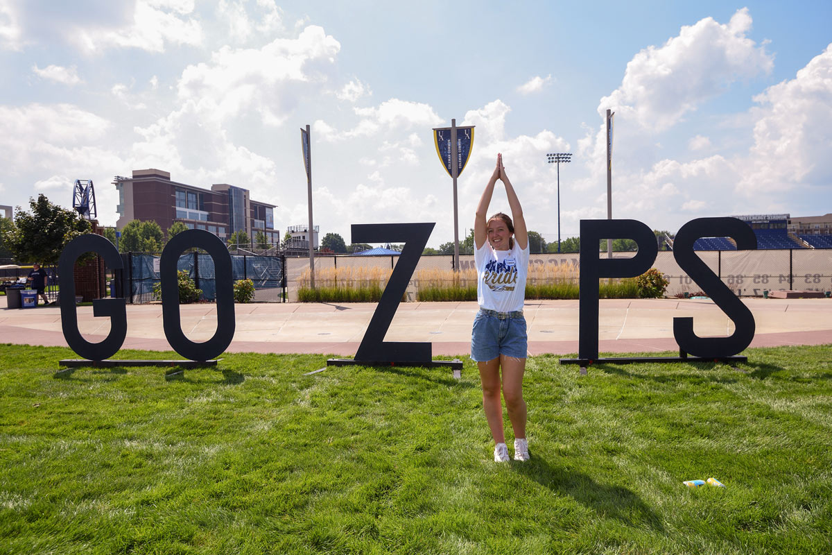 A student makes the I in GO ZIPS, a cutout on Coleman Common