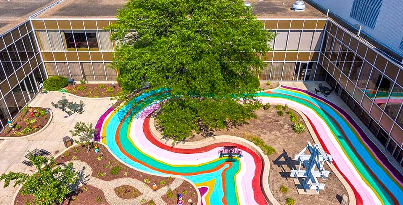 An aerial view of courtyard brightened by a painted rainbow on its sidewalks