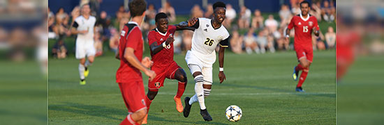 Two soccer players chase a ball during a match