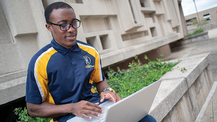 A male student working on a computer outside
