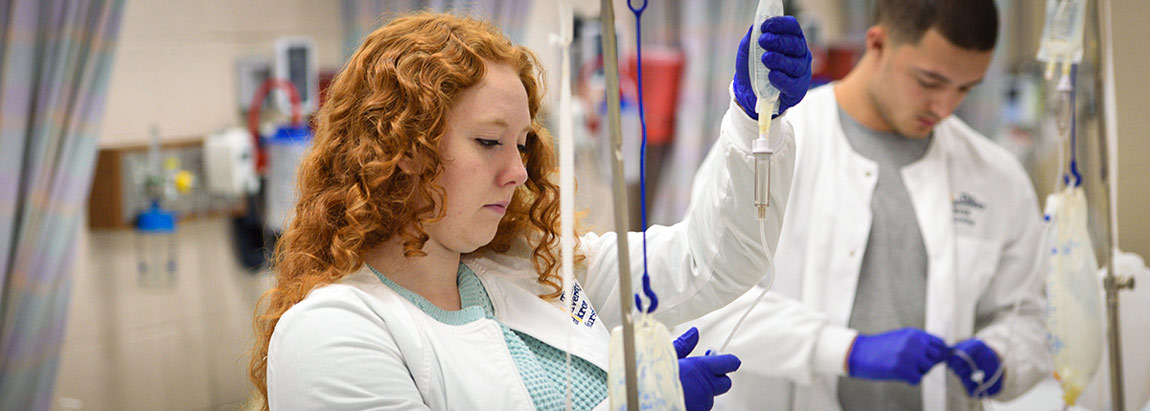 Two nursing students in lab monitor the status of a patient