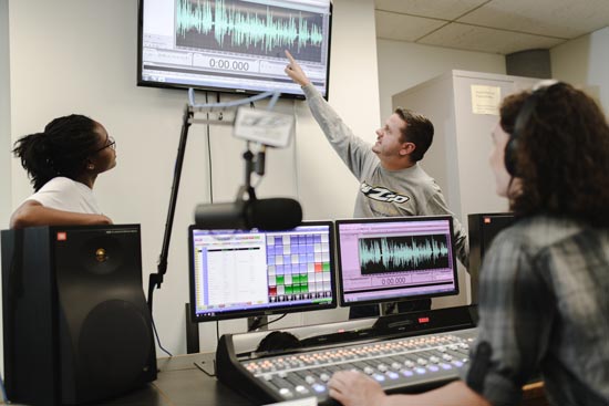 Two student announcers working in the UA WZIP radio studio during an on-air production.