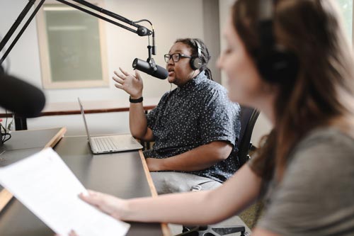 Two student announcers working in the UA WZIP radio studio during an on-air production.