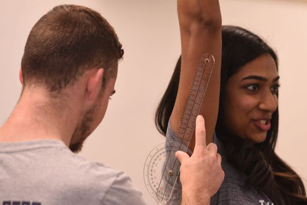 Sports medicine major examining a student's shoulder.