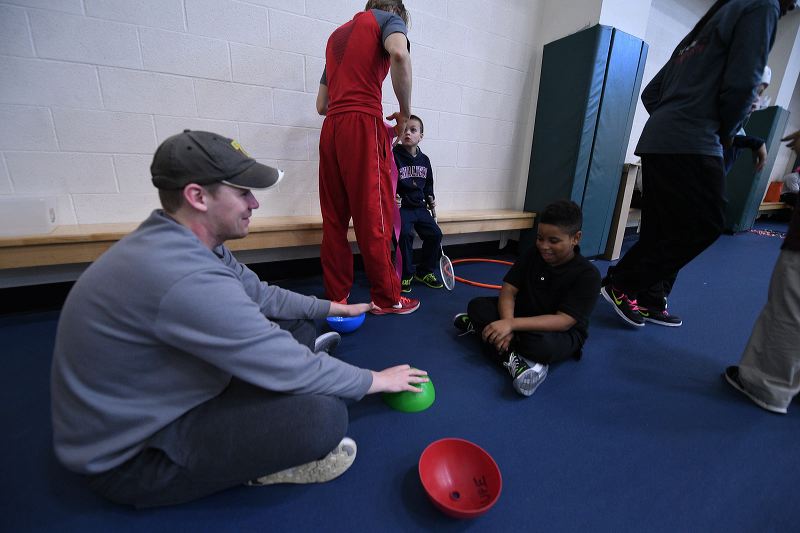 Sports science major working with a child on a mat.