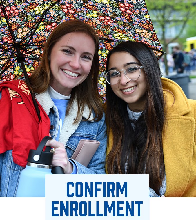 UA students under an umbrella smiling